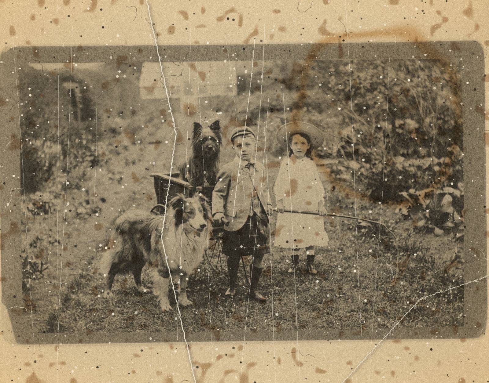 Damaged old print of a boy and girl with two dogs and a wagon in a garden